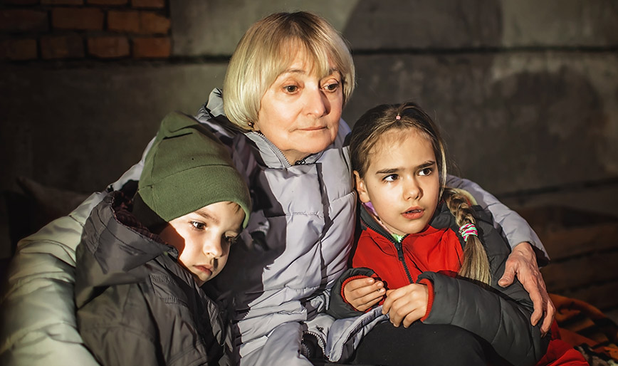 grandmother-hugs-little-ukrainian-kids-they-sit-ou-FGMLM6N